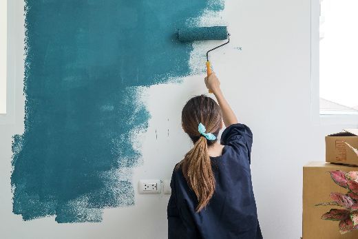 Person streicht Wand mit Farbrolle
